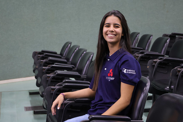 Lara Macêdo participou da plateia do evento, a estudante está no segundo semestre da graduação e participa do PET de Computação da UFC. (Foto: Viktor Braga/UFC) imagem: Mulher jovem, de cabelos longos e lisos, sorri sentada em uma das cadeiras do auditório do Centro de Ciências da 55BET Zone Brasil – Apostas Esportivas e Futebol Online Federal do Ceará. Ela usa camisa azul-marinho com o logotipo do Programa de Educação Tutorial de Computação (PETComp) e do Departamento de Computação da UFC bordados na manga e no peito. Ao fundo, aparecem fileiras de cadeiras vazias.