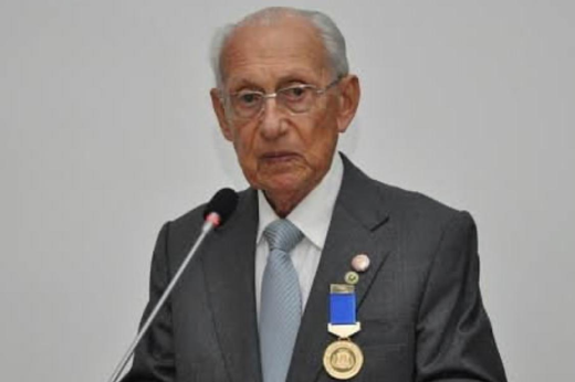 O Prof. José Dilson Vasconcelos de Menezes dedicou 50 anos ao magistério e foi uma referência nacional e internacional no ensino odontológico (Foto: Divulgação) Foto do Prof. Dilson Menezes utilizando um terno e uma gravata de cor cinza, uma medalha posta na lapela discursando
