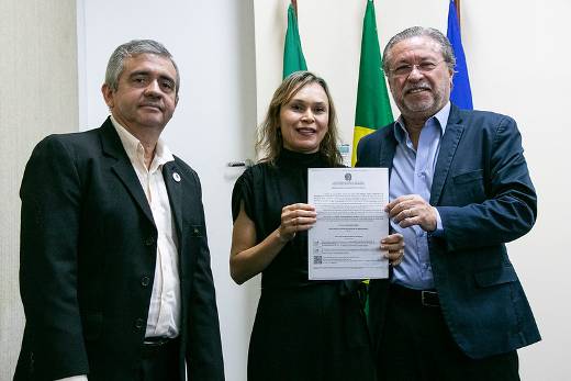 Após mais de 20 anos morando em outro estado, Ana Lúcia retorna para o município onde nasceu, Crateús, para assumir o cargo de assistente em administração (Foto: Ribamar Neto/UFC) Imagem: três pessoas de preto posam para foto, sendo uma mulher ladeada por dois homens