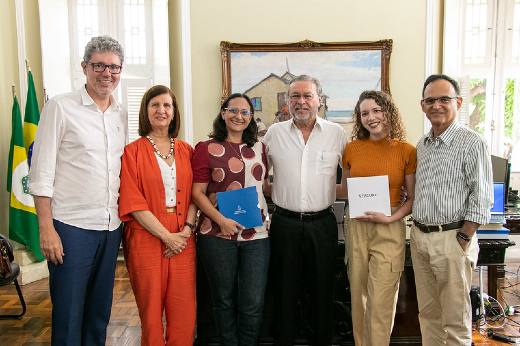 Da esq. para a dir.: Prof. Augusto Albuquerque, Profª Elizabeth Daher, Profª Elenir Ribeiro, reitor Cândido Albuquerque, Ana Beatriz Nogueira e Prof. Rodrigo Porto (Foto: Viktor Braga/UFC) Imagem: Foto posada no gabinete do reitor Cândido Albuquerque com as pesquisadoras e os pró-reitores