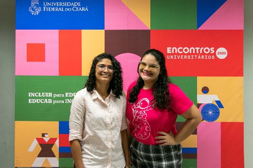 As alunas Thalita Batista e Sarah Soares elogiaram a organização do evento e as experiências que tiveram durante os EU 2023 (Foto: Viktor Braga/UFC) Thalita Batista e Sarah Soares, alunas do Campus de Quixadá, lado a lado, em pé; por trás há um banner do evento (Foto: Viktor Braga/UFC)