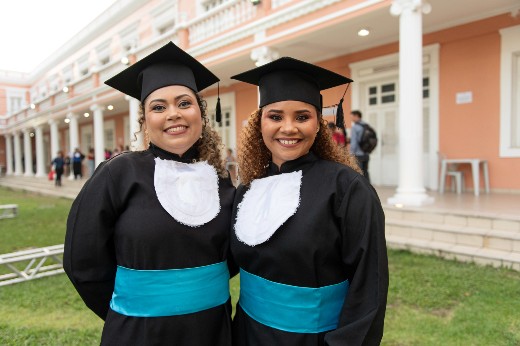 As amigas Carla e Laís desejam o aumento da presença feminina na ciência (Foto: Viktor Braga/UFC) Estudantes Carla e Laís trajando beca no jardim da Reitoria