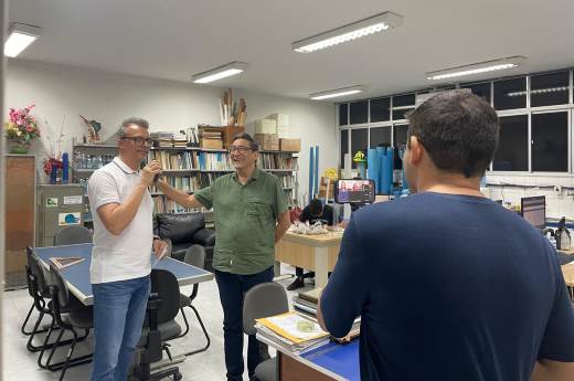 O coordenador do curso de Geologia, Enéas Oliveira Lousada (camisa branca), e o professor Itabaraci (camisa verde), coordenador do Laboratório de Hidrogeologia, apresentam a estrutura física do curso aos avaliadores do MEC (Imagem: Divulgação) Imagem: coordenador Enéas Lousada e outro professor são filmados por um homem numa sala de reunião