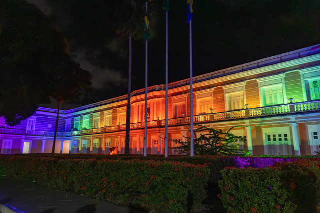 Fachada do prédio da Reitoria da UFC iluminado com luzes coloridas imitando um arco-íris
