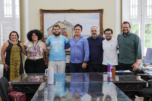 Pessoas que participaram da reunião posando para a foto atrás da mesa do reitor