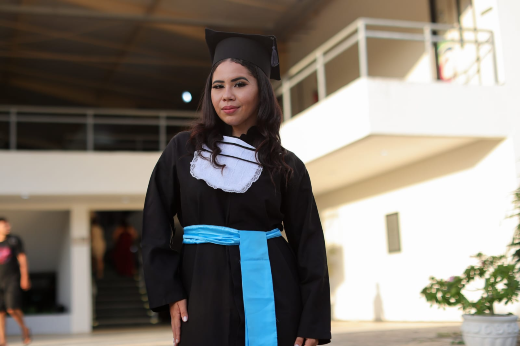 Imagem: estudante vestindo beca posa para foto em frente ao Campus de Crateús