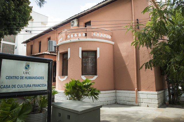 Fachada de uma casa de paredes rosa e janelas marrom. Na lateral, há uma placa Informando Casa de Cultura Francesa