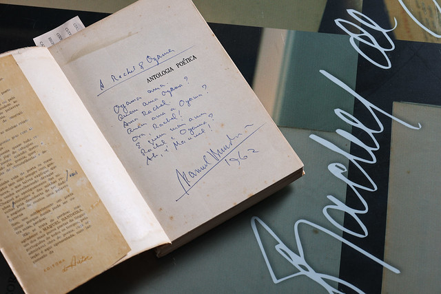 Imagem: livro aberto na folha de rosto exibindo dedicatória de Manuel Bandeira a Rachel de Queiroz 