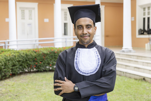 Para Juan Rodrigues, a experiência universitária foi construída tanto pelas oportunidades acadêmicas quanto pelas relações humanas (Foto: Guilherme Silva/UFC) Imagem: jovem negro está de beca e braços cruzados. Ele posa para foto