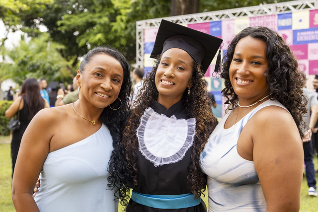 Filha de professora e irmã de uma egressa da própria UFC, Luana Rufino vê sua formatura como continuidade de uma história coletiva (Foto: Guilherme Silva/UFC)a Imagem: jovem negra vestida com beca posa para foto abraçada entre outras duas jovens negras