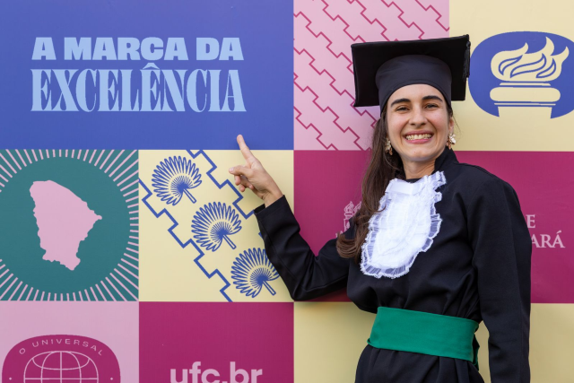 Imagem: Formanda em frente a banner institucional 