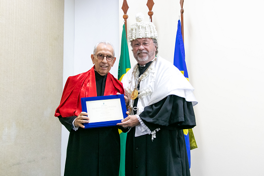 Paulo Ponte é desembargador do Tribunal de Justiça do Estado do Ceará (TJCE) e recebe o título de Professor Emérito (Foto: Gutierrez Reges/UFC Informa) Imagem: Homem com roupa preta e capa branca posa ao lado de homem com vestido preto e capa vermelha que segura o título