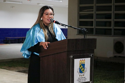 Em sua fala como representante dos docentes, a professora Anna Beatriz Marques ressaltou iniciativas de fortalecimento da participação feminina na área de Ciência, Tecnologia e Engenharia (Foto: Ribamar Neto/UFC) Imagem: Professora discursa no púlpito durante a colação, com veste talar azul