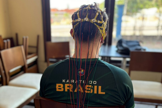 Atletas da Seleção de Karatê foram avaliados por meio de de eletroencefalograma (Foto: Letícia Clemente/Divulgação) Imagem: Foto de atleta de Karatê, sentado, de costas, com vários fios presos ao couro cabeludo (Foto: Letícia Clemente/ Divulgação)