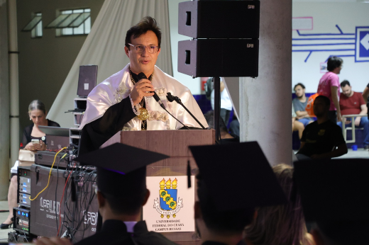 Na ocasião, o reitor Custódio Almeida convocou os agora graduados a serem também protagonistas e continuadores dessa missão (Foto: Viktor Braga/UFC) Imagem: reitor com veste talar branca discursa em púlpito