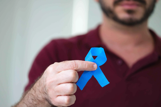Os pesquisadores investigam a utilização de nanopartículas para tratar o câncer de próstata (Foto: Viktor Braga/UFC Informa) Imagem: A imagem mostra um homem vestindo uma camiseta polo de cor vinho. Ele está segurando um laço azul entre os dedos, próximo à câmera. O rosto dele está parcialmente fora de foco, destacando o laço azul como o elemento principal da imagem. Esse laço é frequentemente associado à conscientização sobre o câncer de próstata ou à saúde masculina em geral, como na campanha Novembro Azul