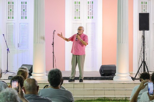 "Estamos aqui pelo que representa a nossa história, os nossos ideais, nossos sonhos", resumiu José Genoíno. Ex-deputado federal pelo PT, ele foi militante estudantil na UFC e perseguido pela ditadura militar (Foto: Ribamar Neto/UFC) Imagem: um homem idoso, de camisa rosa e calça marrom, fala ao microfone para uma plateia à sua frente, enquanto gesticula. Atrás dele aparecem portas de um casarão antigo, com paredes rosas