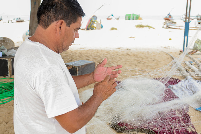 Parceria entre Labomar e Fortescue também envole a comunidade de pescadores e marisqueiras da Praia do Pecém (Foto: Ribamar Neto/UFC) Imagem: pescador costura rede de pesca