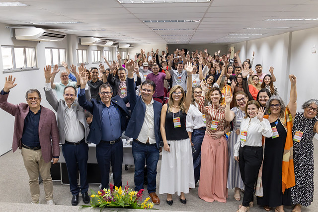 Imagem: grupo de pessoas reunidas levantam a mão