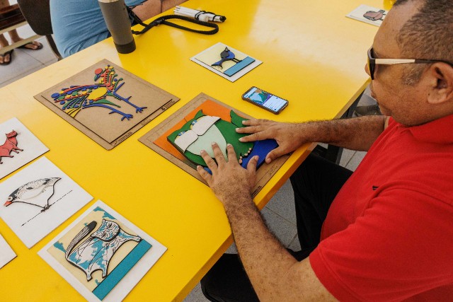 O App Mauc é um audioguia que reúne audiodescrição, áudios em inglês e áudios gerais sobre um conjunto de obras do circuito expositivo (Foto: Ribamar Neto/Secom-UFC) Imagem: Homem fazendo leitura em peça tátil de uma obra de Aldemir Martins