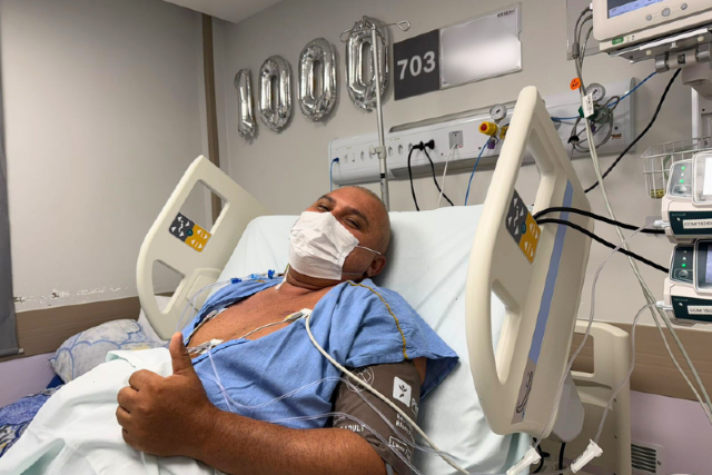 Imagem: paciente transplantado faz gesto de positivo em cama de hospital