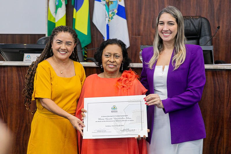 A professora Goretti Vasconcelos, ao receber a homenagem ao lado da vereadora Adriana Almeida e da deputada estadual Larissa Gaspar. Foto Ribamar Neto/UFC Informa